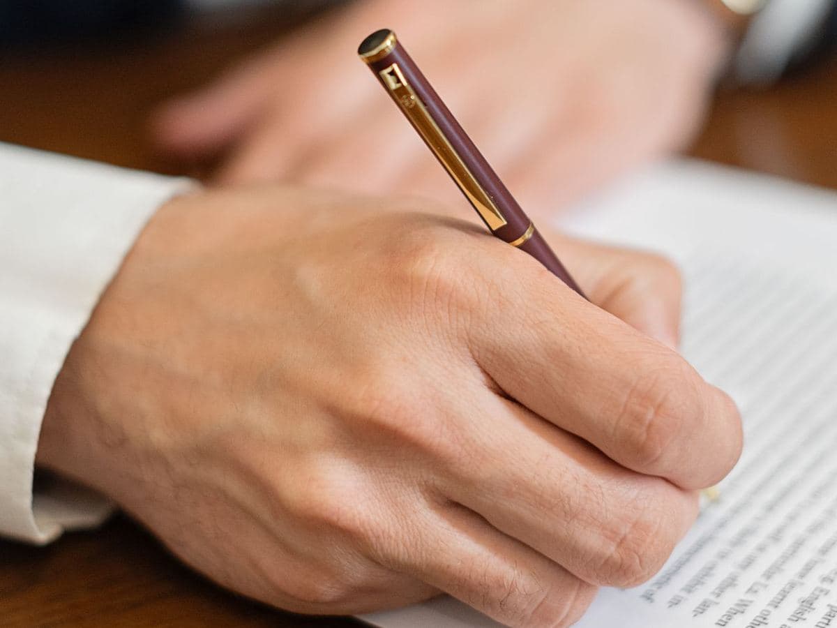 Mano firmando una traducción jurada con pluma sobre el documento
